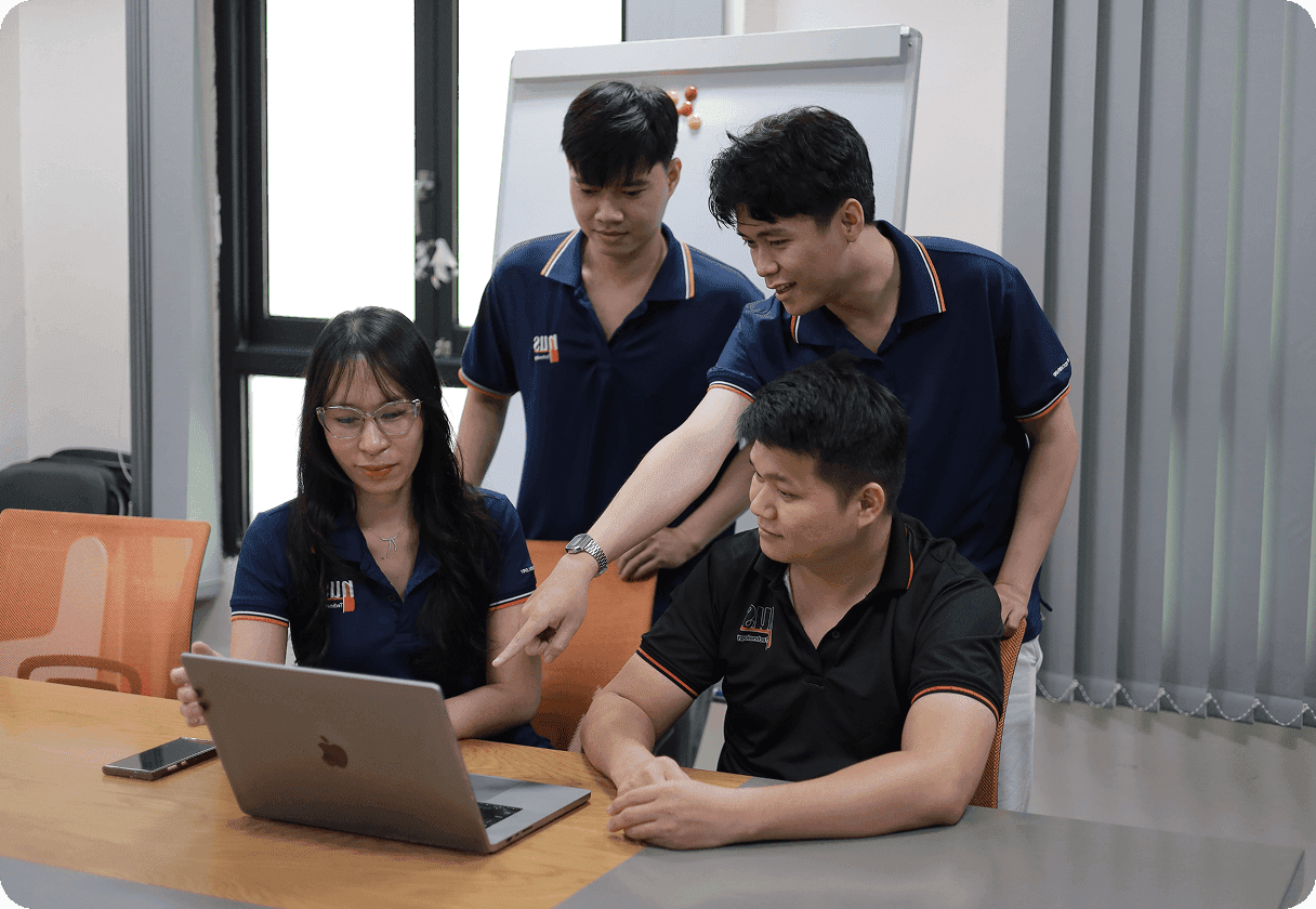 Four people around a laptop discussing work.