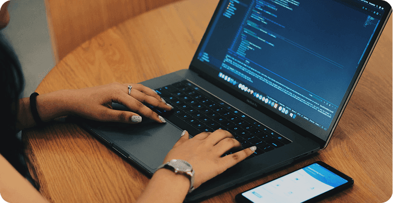 Developer coding on laptop with phone nearby