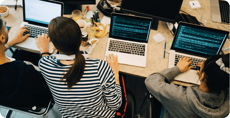 Developers working on laptops with code on their screens, viewed from above