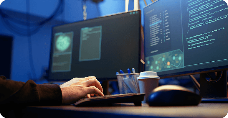 Developer coding on dual monitors in a dark office