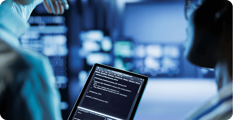 Engineers reviewing code on a tablet in a data center