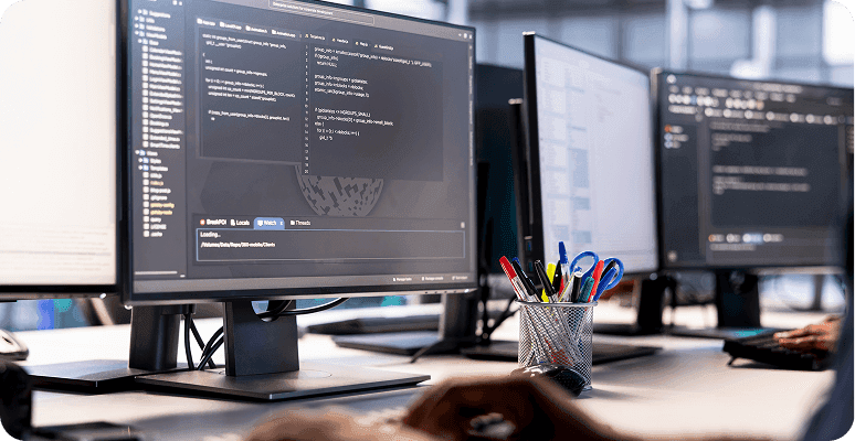 Multiple computer monitors displaying code in an office