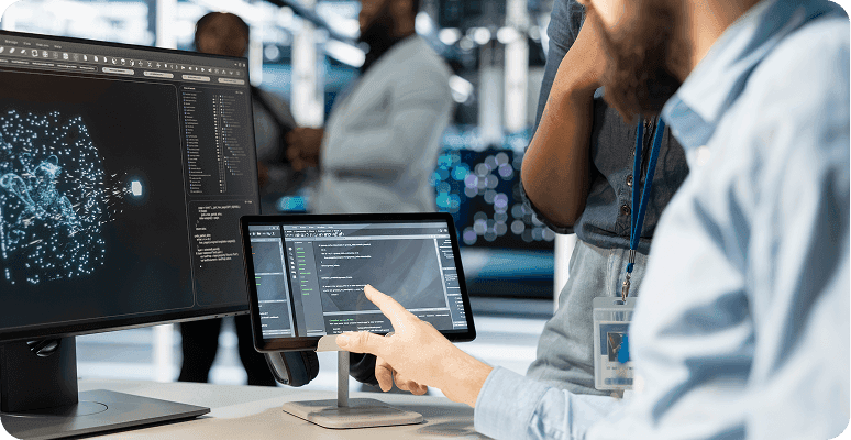 Engineer reviewing data on monitor and tablet.